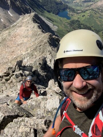 man smiling while rock climbing 