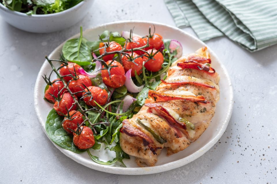 A grilled chicken dinner with tomato salad